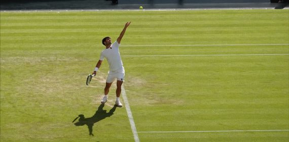 Carlos Alcaraz lanza la bola al aire para sacar sobre la hierba de la pista central de Wimbledon