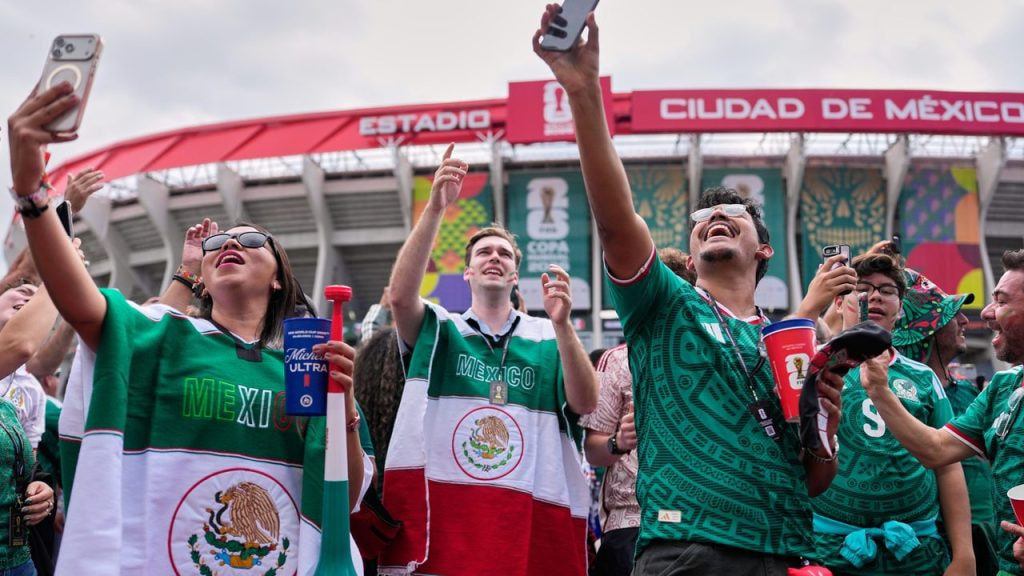 Aficionados mexicanos se graban con su teléfono en los aledaños del Estadio Azteca antes del México - Chequia.