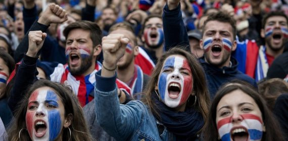 Aficionados con la cara pintada en colores de una selección gritando en una protesta