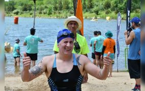 Una nadadora con gorro y gafas levanta los dos pulgares al salir del agua tras una prueba de aguas abiertas