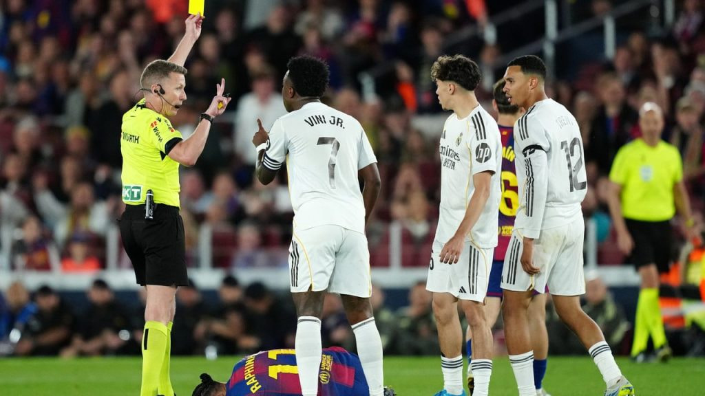 El árbitro español Alejandro Hernández Hernández saca una tarjeta amarilla durante un Clásico.