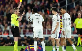 El árbitro español Alejandro Hernández Hernández saca una tarjeta amarilla durante un Clásico.
