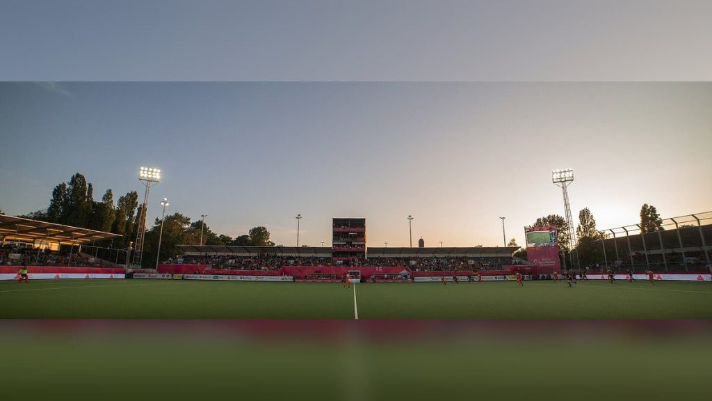 Vista general de un estadio de hockey al atardecer, con la grada llena y los focos encendidos