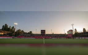 Vista general de un estadio de hockey al atardecer, con la grada llena y los focos encendidos