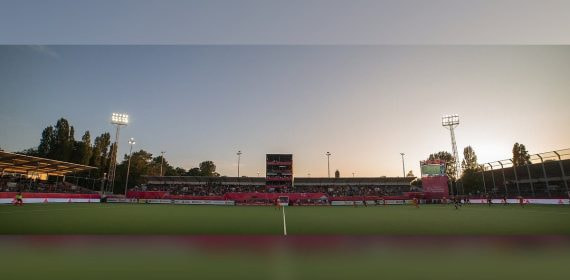 Vista general de un estadio de hockey al atardecer, con la grada llena y los focos encendidos