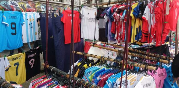 Camisetas de fútbol de selecciones y clubes colgadas a la venta en un puesto de mercado callejero