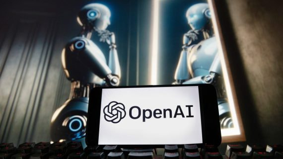Logotipo de OpenAI (ChatGPT) en un móvil sobre un teclado y un androide al fondo mirándose en un espejo.