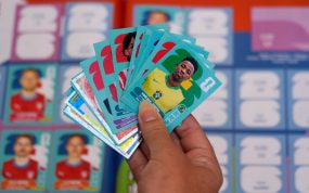 Un aficionado con varios cromos del Mundial 2026 en la mano, entre ellos el de Vinícius Jr. con Brasil.