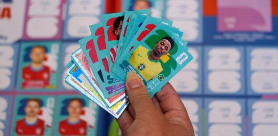 Un aficionado con varios cromos del Mundial 2026 en la mano, entre ellos el de Vinícius Jr. con Brasil.