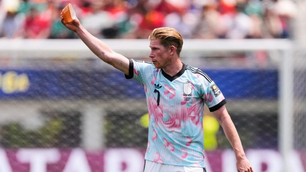 Kevin de Bruyne ofrece el brazalete de capitán antes de ser sustituido en el partido ante España.