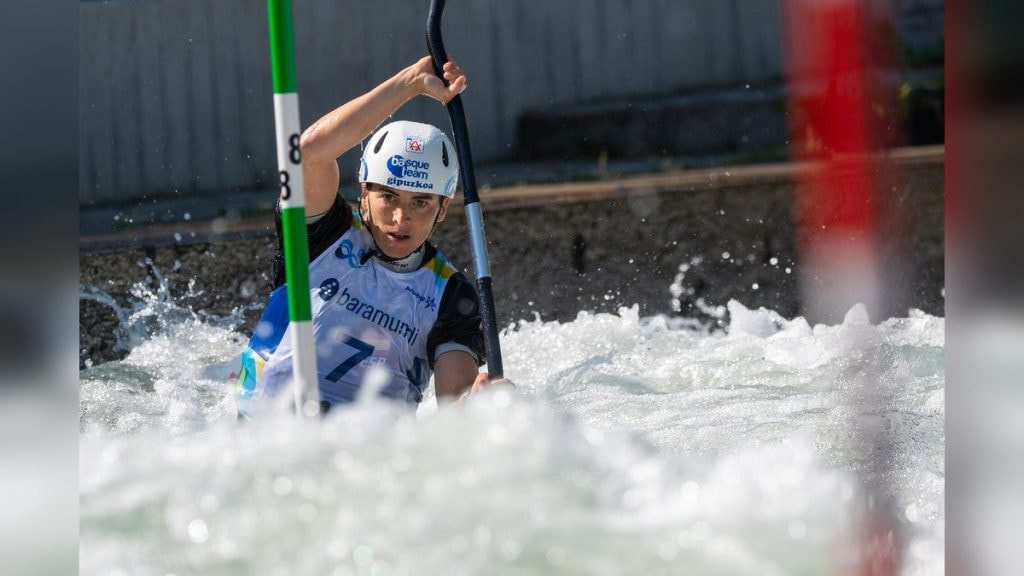 Una palista con casco del Basque Team desciende entre las palas verdes y rojas de una manga de eslalon