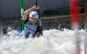 Una palista con casco del Basque Team desciende entre las palas verdes y rojas de una manga de eslalon