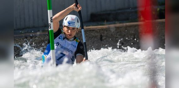 Una palista con casco del Basque Team desciende entre las palas verdes y rojas de una manga de eslalon