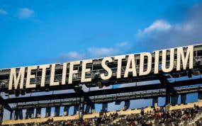 Letras con el nombre del MetLife Stadium sobre las gradas del estadio durante un evento deportivo.