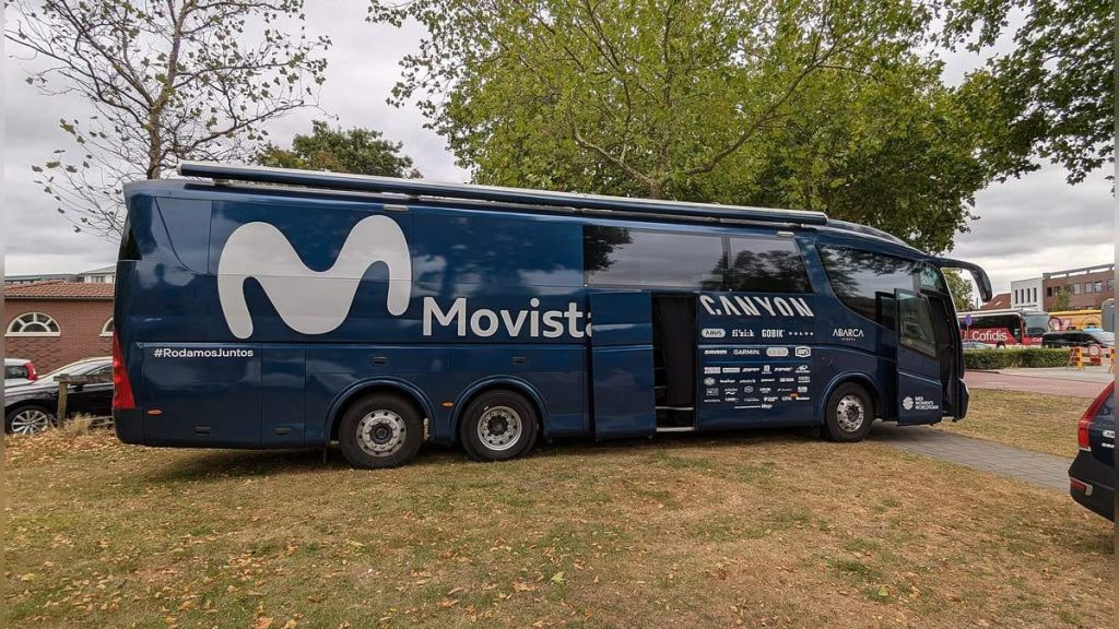 El autobús del equipo ciclista Movistar aparcado bajo unos árboles antes de una etapa