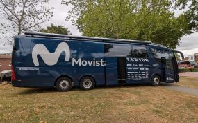 El autobús del equipo ciclista Movistar aparcado bajo unos árboles antes de una etapa