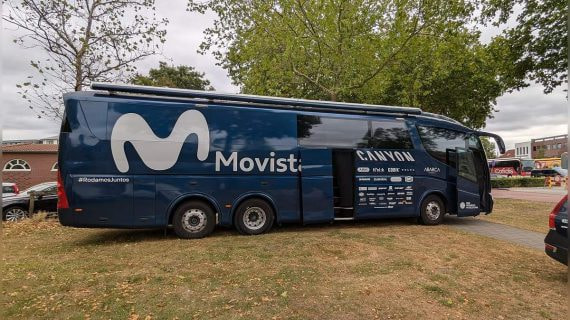 El autobús del equipo ciclista Movistar aparcado bajo unos árboles antes de una etapa