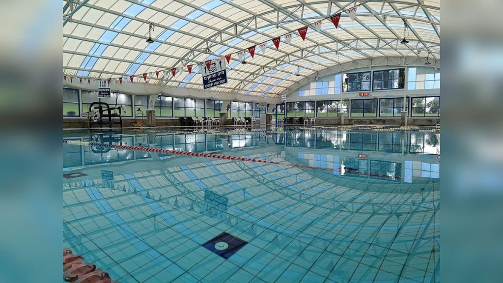 Una piscina cubierta vacía bajo una cubierta acristalada, con las corcheras puestas