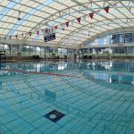 Una piscina cubierta vacía bajo una cubierta acristalada, con las corcheras puestas