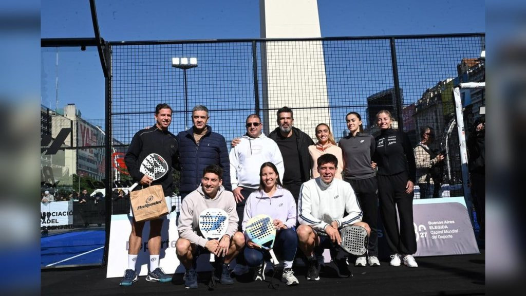 Jugadores y directivos de pádel posan con sus palas en una pista montada junto al Obelisco de Buenos Aires