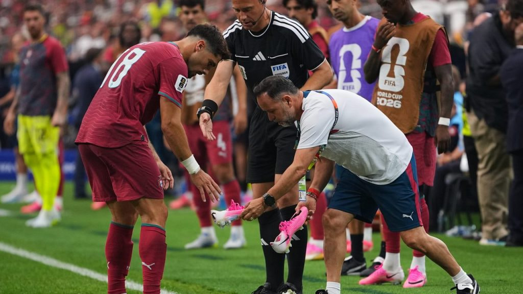 Pedro Neto, de Portugal, se cambia sus botas rosas por otras durante el transcurso del partido ante España del Mundial 2026.
