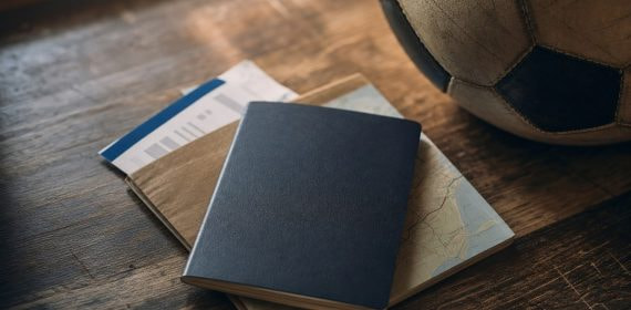Pasaporte, tarjeta de embarque y un balón de fútbol sobre una mesa de madera, listos para viajar al Mundial 2026