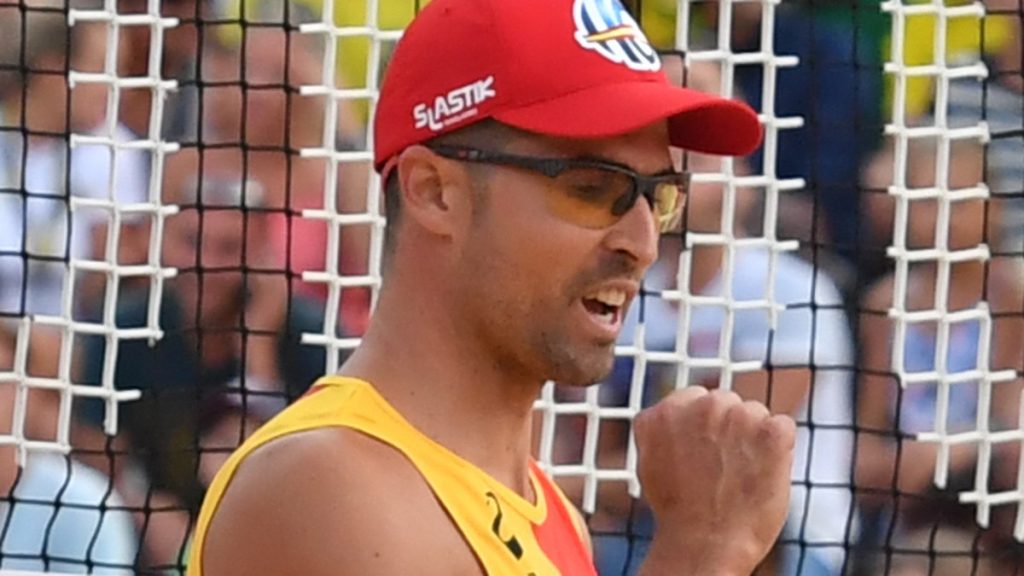 Adrián Gavira, con gorra roja y camiseta de España, aprieta el puño para celebrar un punto en la arena.