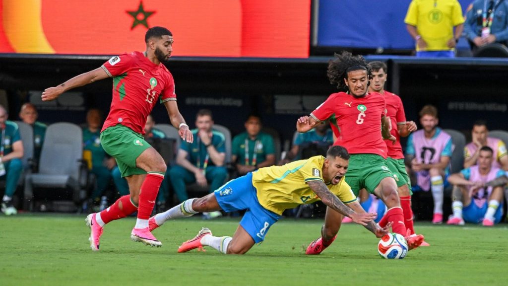 Bruno Guimarães cae al césped disputando el balón ante dos rivales de Marruecos en el Mundial 2026.