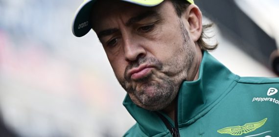 Fernando Alonso, con la equipación de Aston Martin, baja la mirada con gesto de resignación.