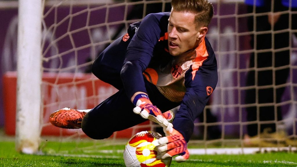 Marc-André ter Stegen se estira para blocar un balón a ras de césped junto al poste de su portería