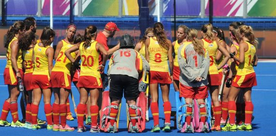 Las jugadoras de la selección española femenina de hockey hierba forman corro con el técnico sobre el campo azul