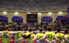 Dos equipos alineados ante la red en un pabellón lleno y forrado de vallas de la Volleyball Nations League