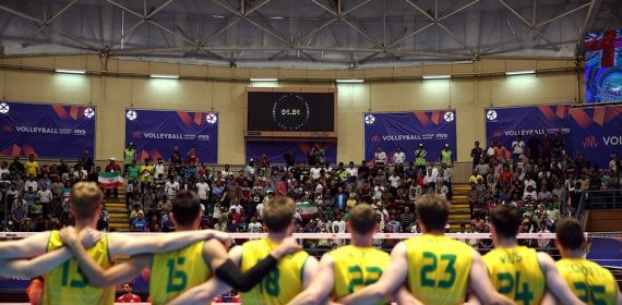 Dos equipos alineados ante la red en un pabellón lleno y forrado de vallas de la Volleyball Nations League