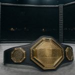 Cinturón de campeón de artes marciales mixtas apoyado en la lona de un octógono vacío