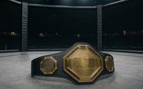Cinturón de campeón de artes marciales mixtas apoyado en la lona de un octógono vacío