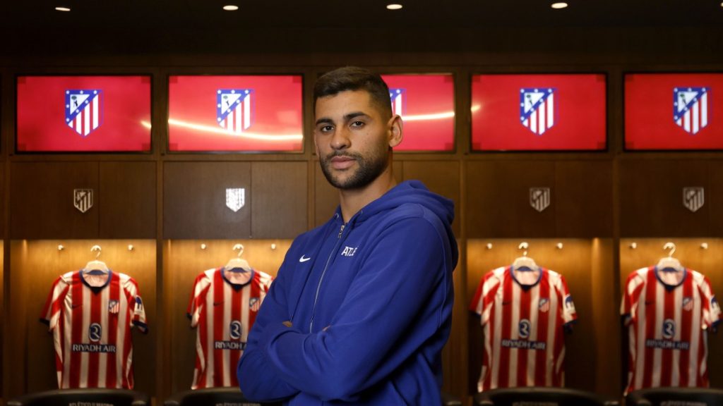 Cristian 'Cuti' Romero posa con los brazos cruzados en el vestuario del Atlético de Madrid, ante las camisetas colgadas
