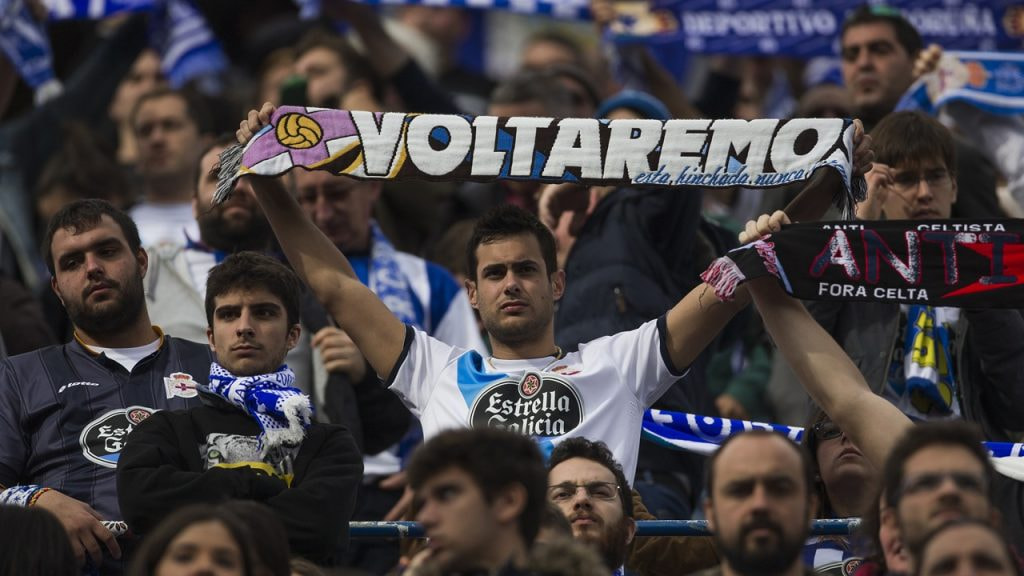 Un aficionado del Dépor exhibe una bandera con el lema 'Voltaremos' durante un partido de su equipo.