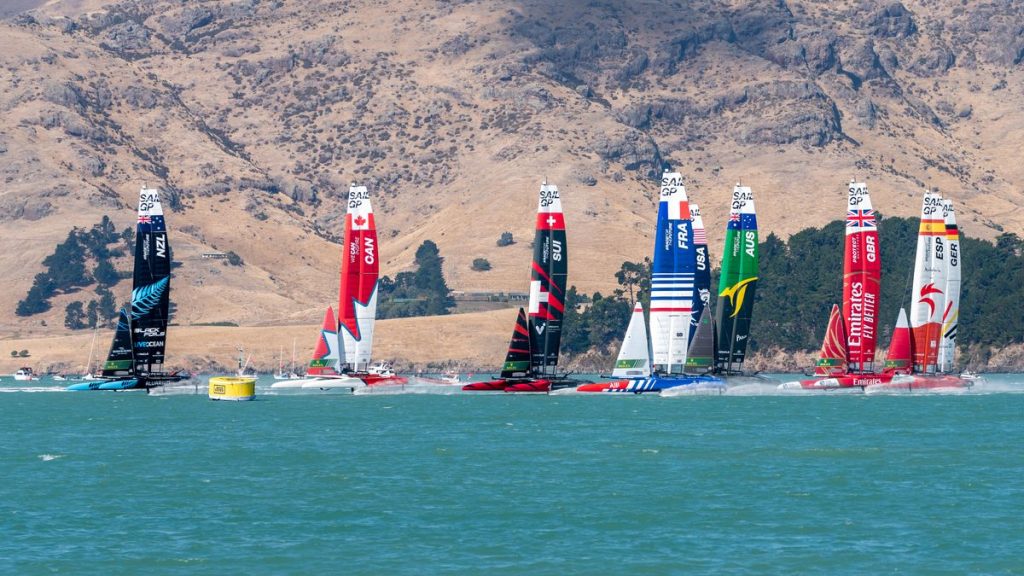 La flota de catamaranes F50 de SailGP navega en línea durante una regata, con el barco español a la derecha