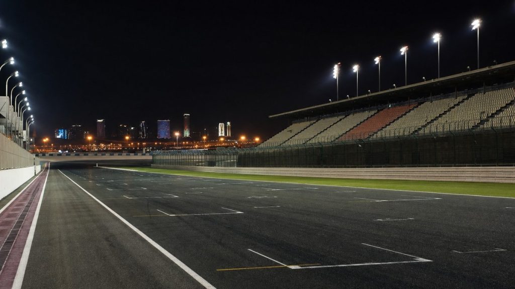 Recta de meta iluminada de un circuito de motociclismo vacío de noche en el desierto