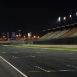 Recta de meta iluminada de un circuito de motociclismo vacío de noche en el desierto