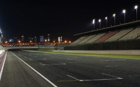 Recta de meta iluminada de un circuito de motociclismo vacío de noche en el desierto