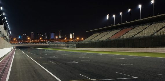 Recta de meta iluminada de un circuito de motociclismo vacío de noche en el desierto
