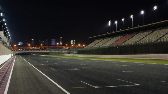 Recta de meta iluminada de un circuito de motociclismo vacío de noche en el desierto
