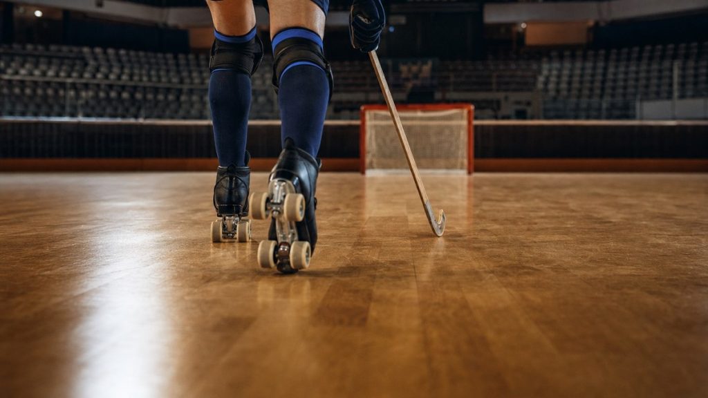 Las piernas y los patines de un jugador de hockey patines avanzan con el stick hacia una portería vacía
