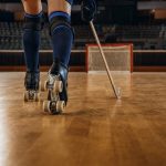 Las piernas y los patines de un jugador de hockey patines avanzan con el stick hacia una portería vacía