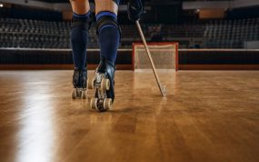 Las piernas y los patines de un jugador de hockey patines avanzan con el stick hacia una portería vacía