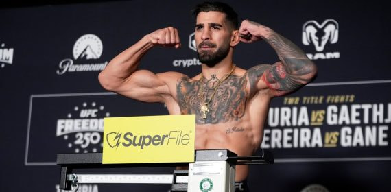 Ilia Topuria flexiona los brazos sobre la báscula durante el pesaje oficial del UFC Freedom 250