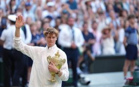 Jannik Sinner saluda al público con el trofeo de ganador de Wimbledon 2026 en sus brazos.