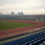Estadio de atletismo vacío con el pebetero apagado sobre la grada al atardecer