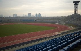 Estadio de atletismo vacío con el pebetero apagado sobre la grada al atardecer